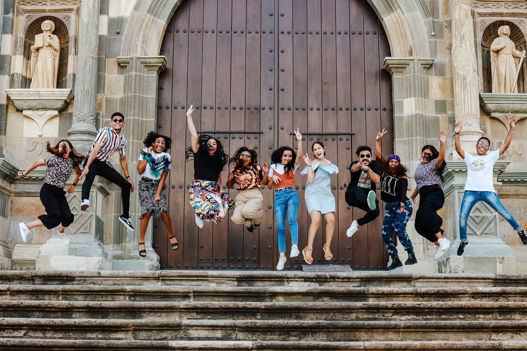 A group of friends jumping for joy on the steps outside
